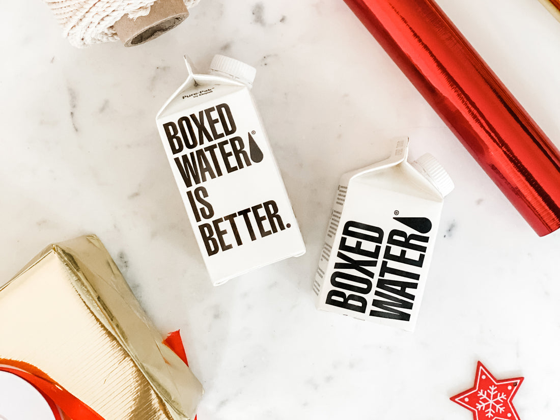 Boxed Water, red wrapping paper and a red Christmas Cookie on a table