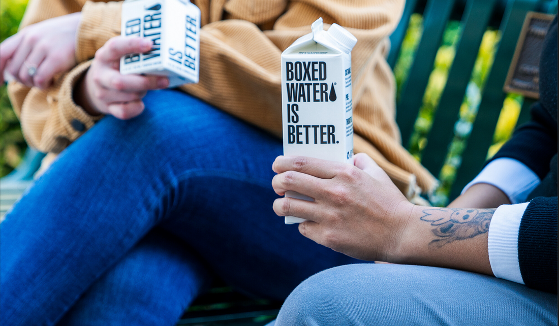 Two people sitting down holding a Boxed Water