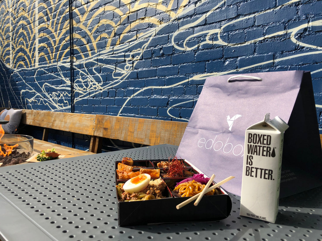 Boxed Water Box on an outdoor table next to a bento box