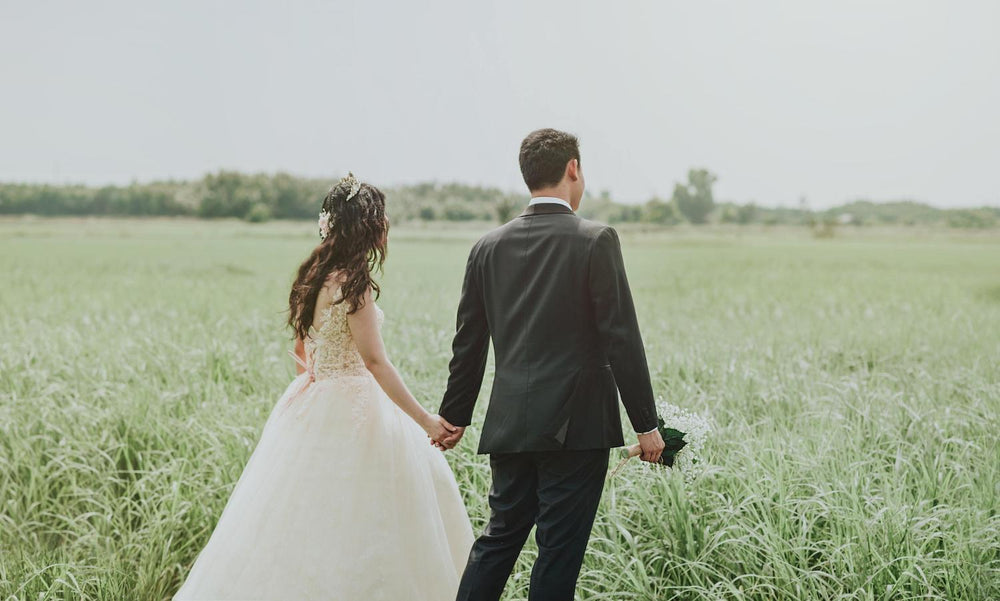 Man and Woman holding hands at a wedding in a field 