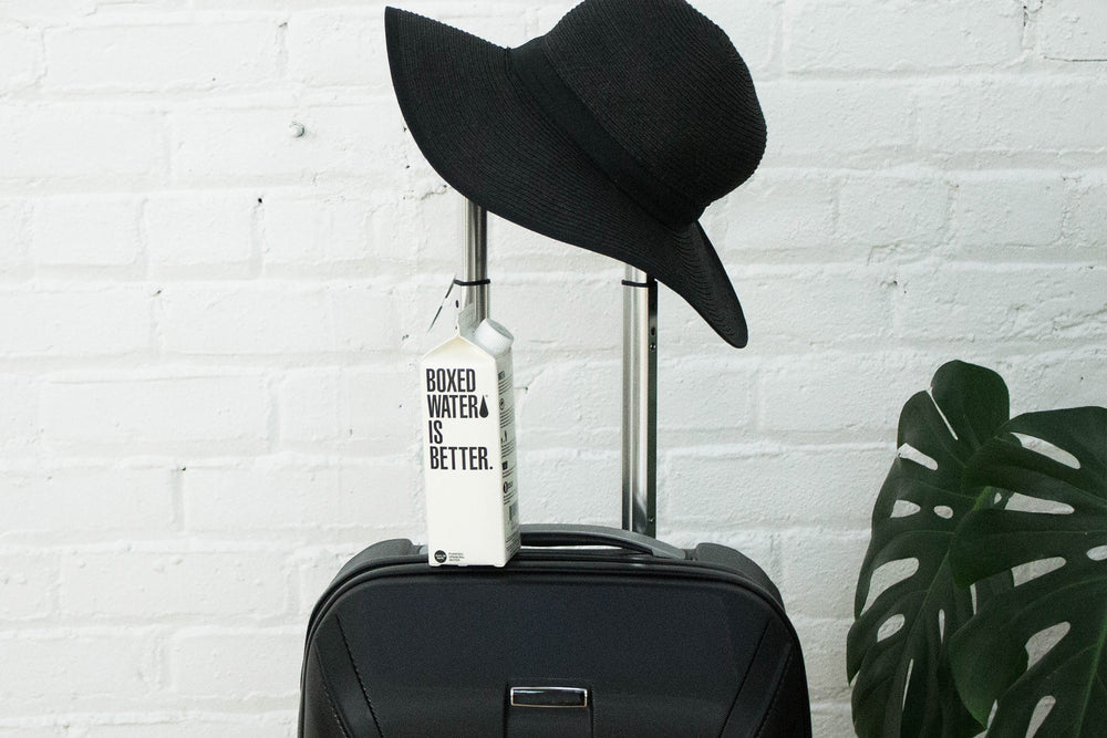 Boxed Water and a hat on a suitcase