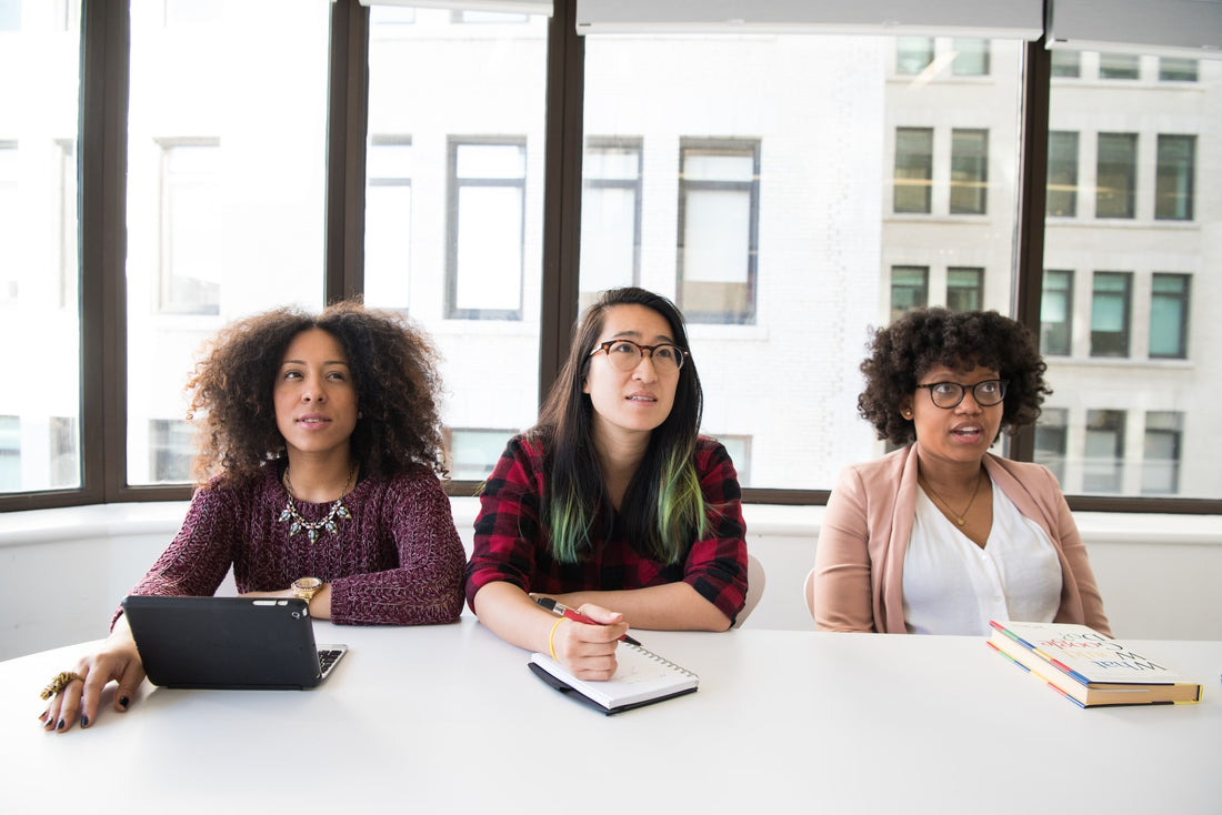 Three women writing notes in a meeting