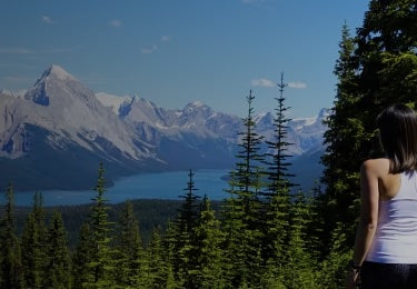 Girl looking over forest and mountains