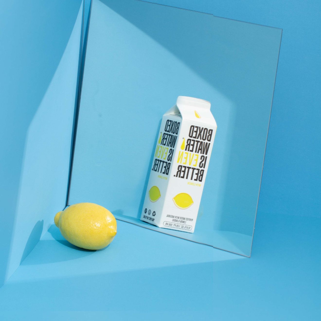 a lemon and lemon flavored Boxed Water in front if a mirror 