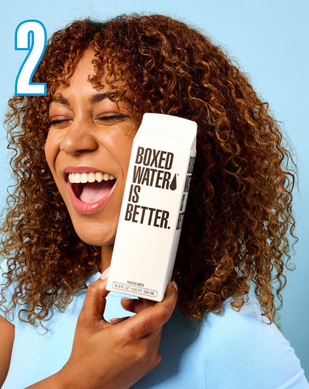 Number 2 with smiling girl in blue shirt holding Boxed Water carton