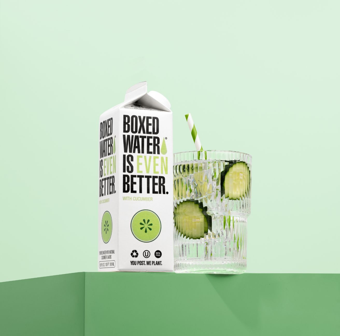 A box and glass of Cucumber Boxed Water in front of a green background