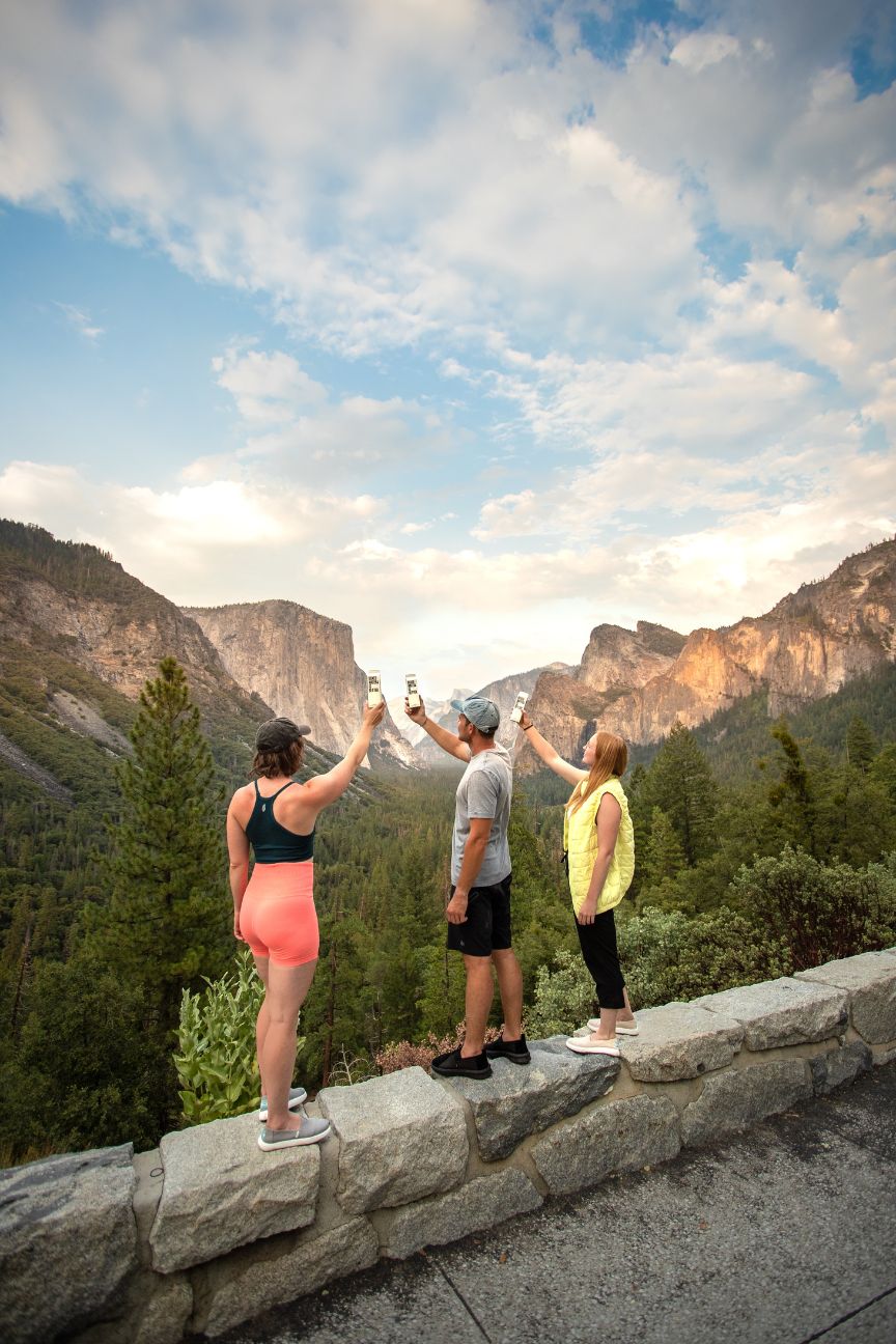 Three travelers holding Boxed Water in the air in Yosemite National Park 