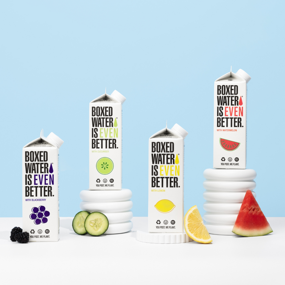 Flavored Boxed water on pedestals with fruit slices next to them 