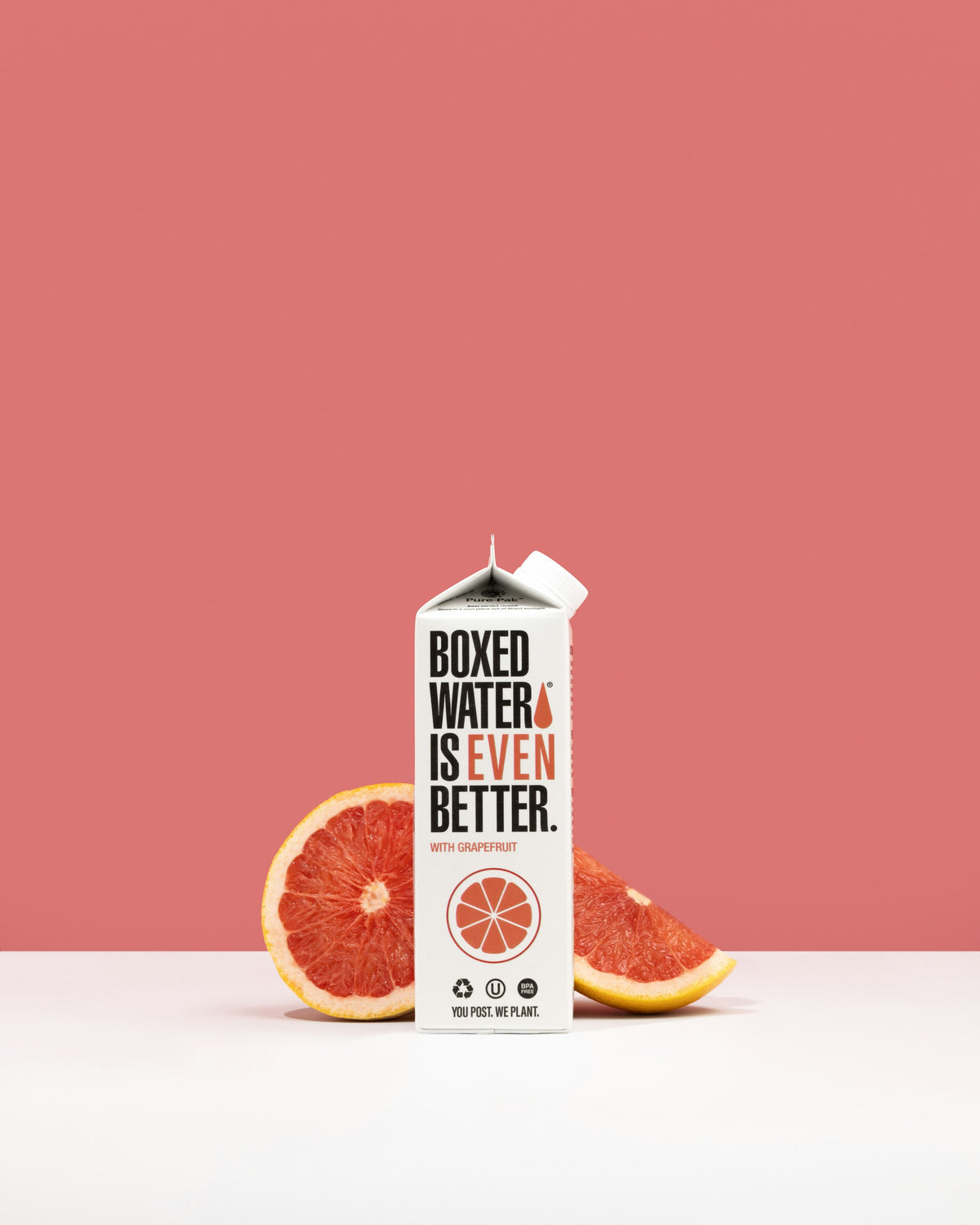 Grapefruit Boxed Water with sliced grapefruit on pink background