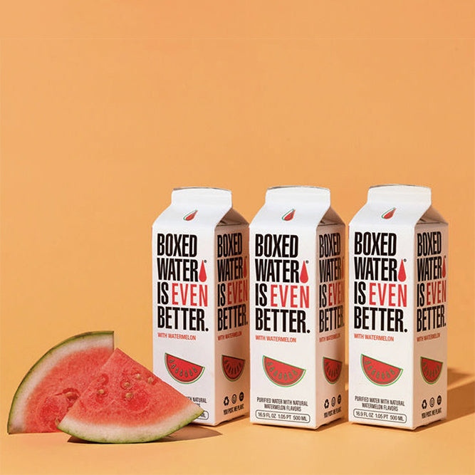 Boxed Water Is Better watermelon flavored cartons with fresh slices of watermelon and orange background