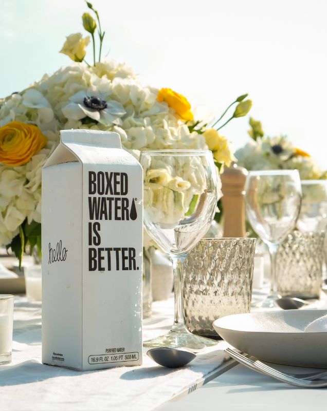 Boxed Water carton at wedding table with white floral arrangement