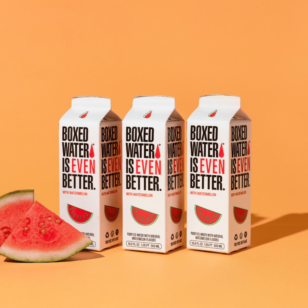 Watermelon flavored boxed waters with fresh cut watermelon with orange background