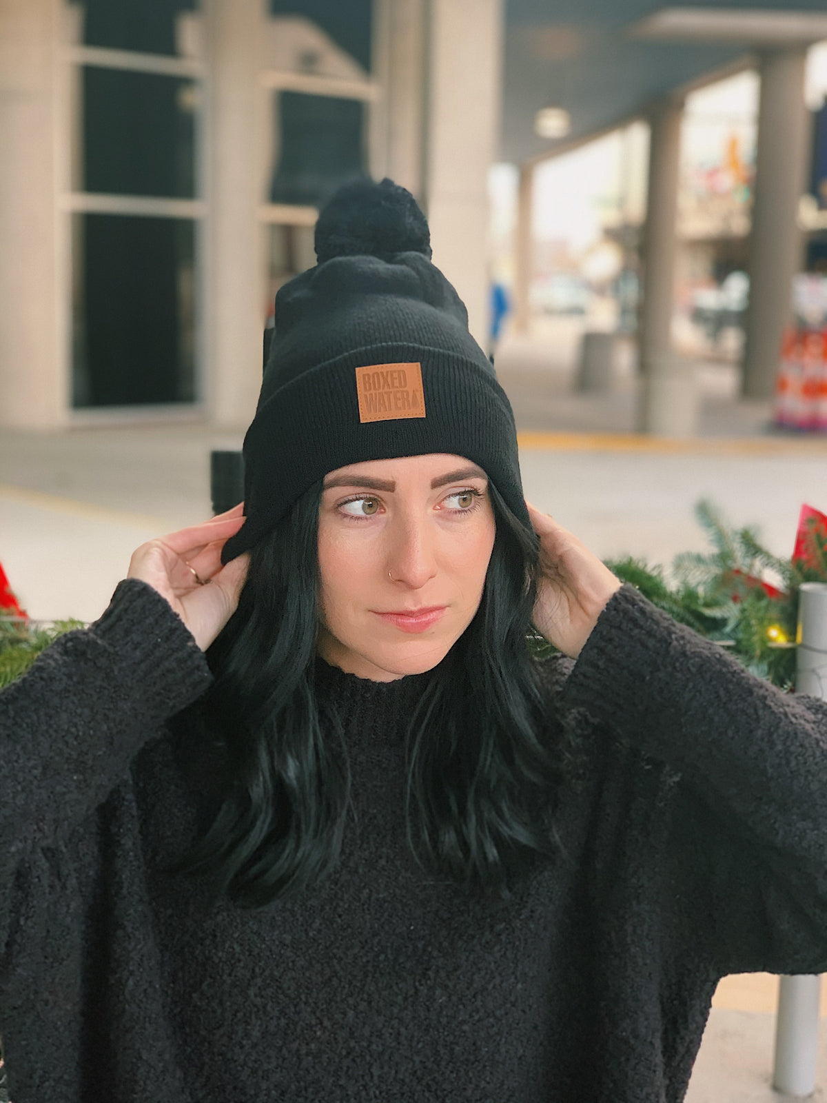 woman slightly smiling wearing black beanie hat