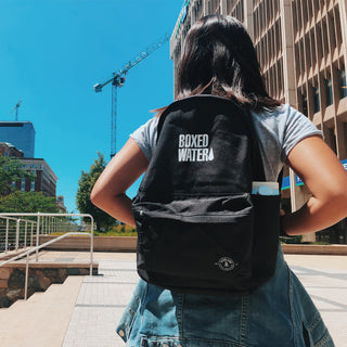 girl with black backpack walking in city